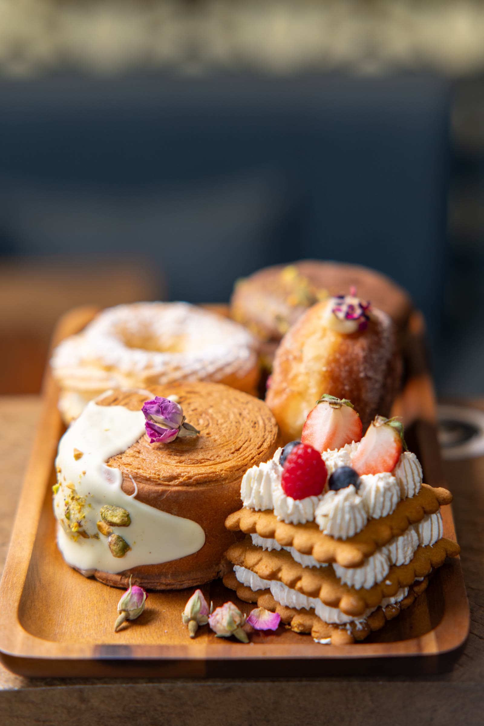 Close view of mille-feuille, cruller, and berry shortcake stack on a wooden tray
